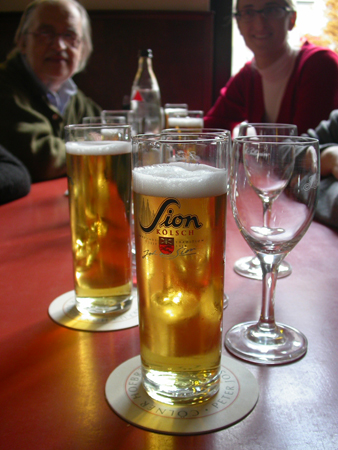 Bicchieri di Kölsch Sion in un locale di Colonia: in questa foto, sullo sfondo, Pietro Chianchiano, il fondatore di Tsport (scomparso nel 2017), con una nostra giornalista. 